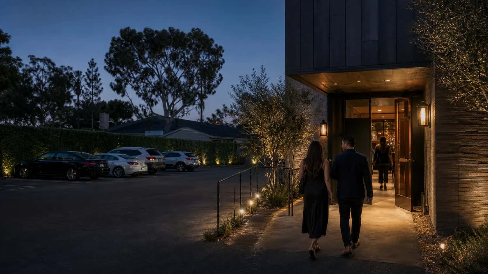 Parking Arrival Hero at House of Legends Illustrative evening restaurant arrival with a rear parking lot, accessible path, and warmly lit entrance in Encino